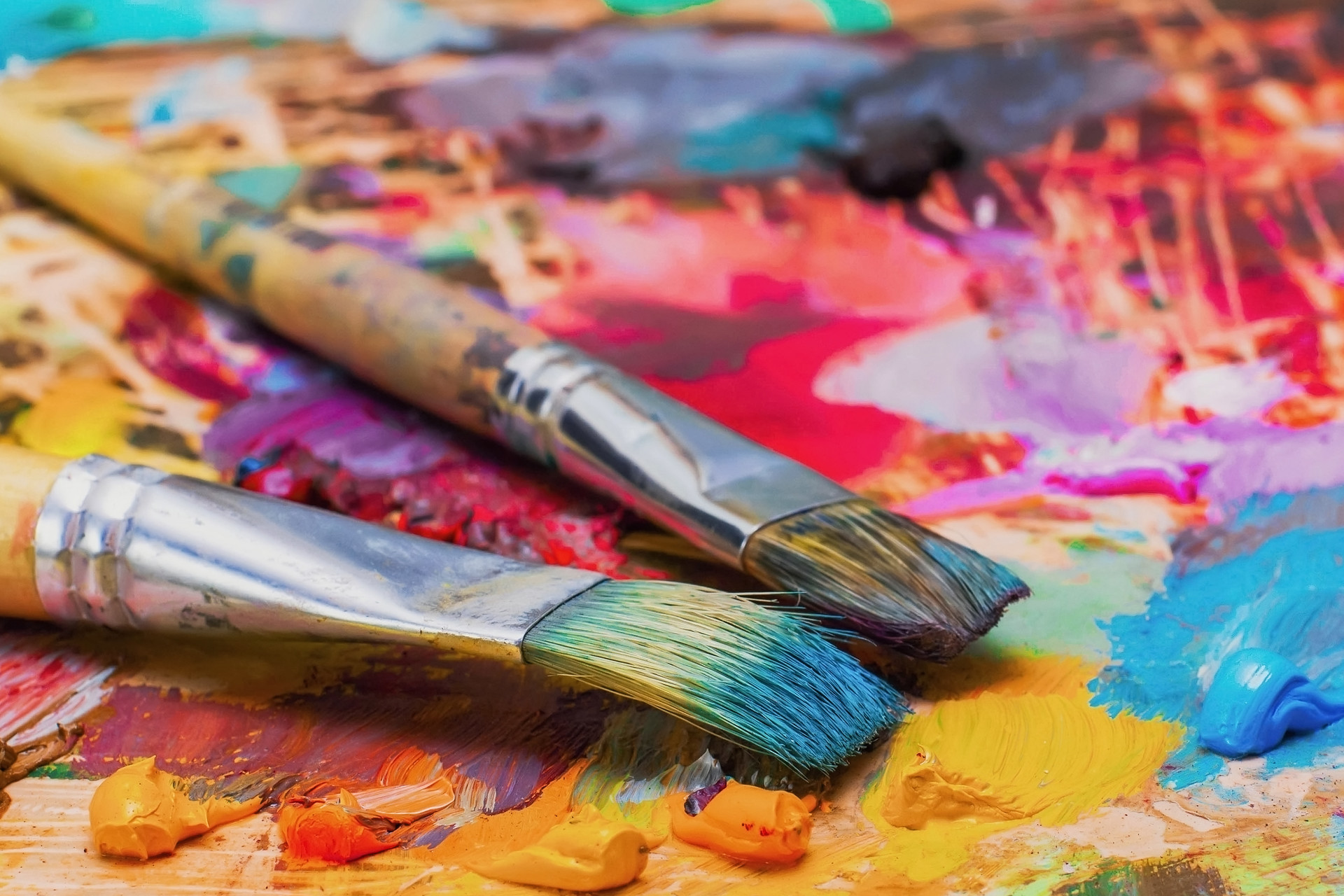 Used brushes on an artist’s palette of colorful oil paint for drawing and painting